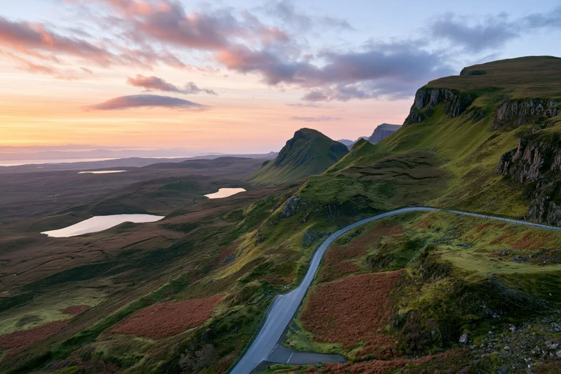 Winding single-track road through mountainous highland landscape at sunset