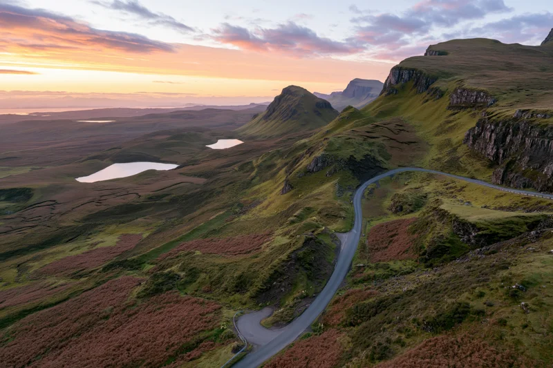 Winding single-track road through mountainous terrain at sunset in the Scottish Highlands