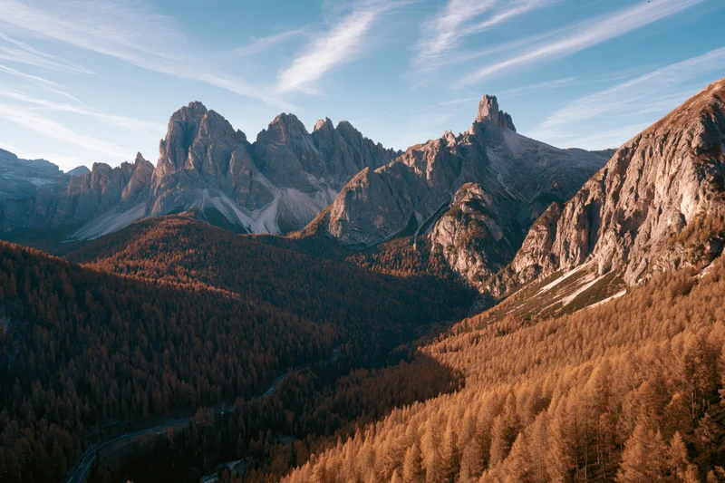 Aerial view of jagged dolomite peaks and autumn forested valley in italy