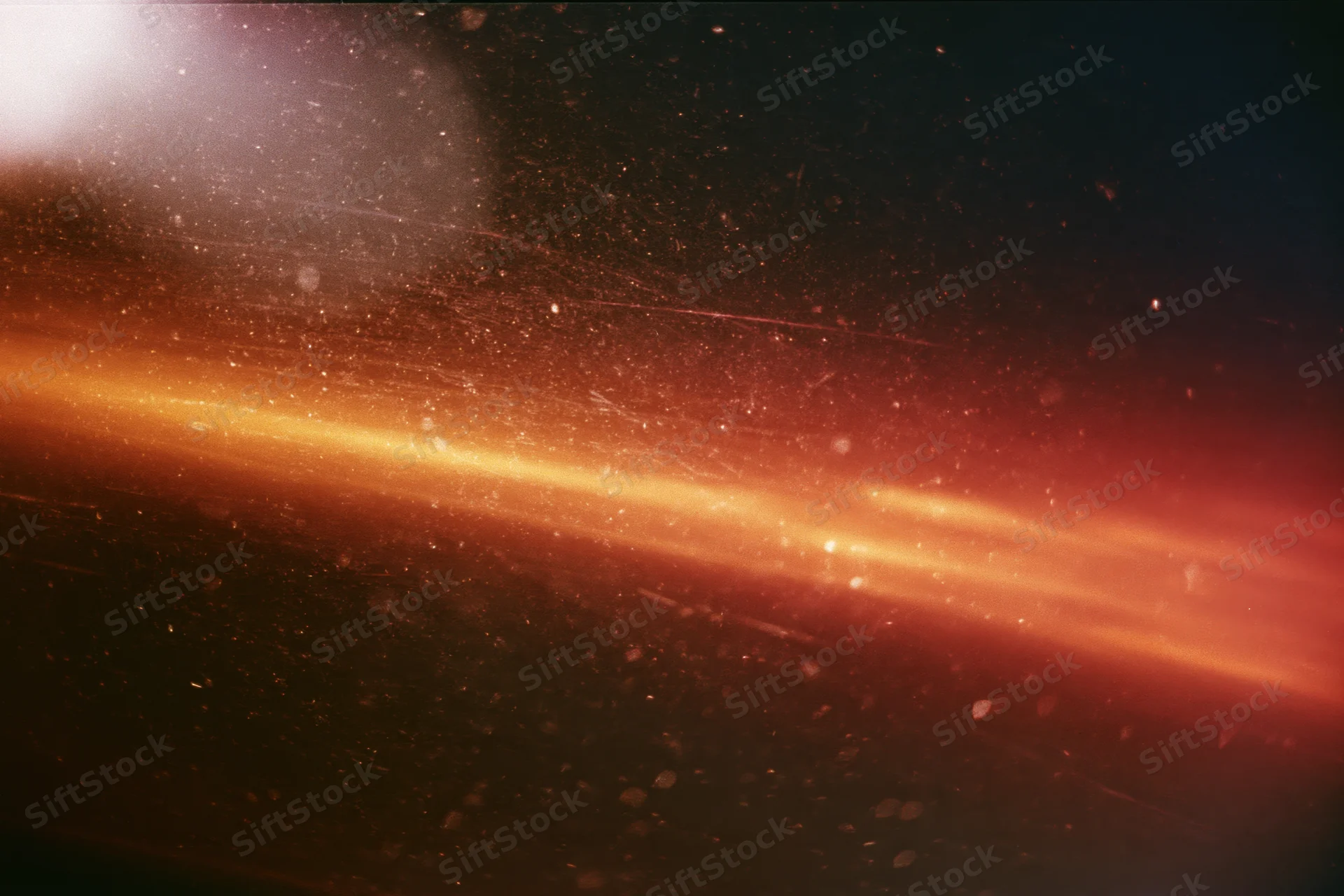 Warm light leak bleeding across dark analog film frame with visible grain and floating particles