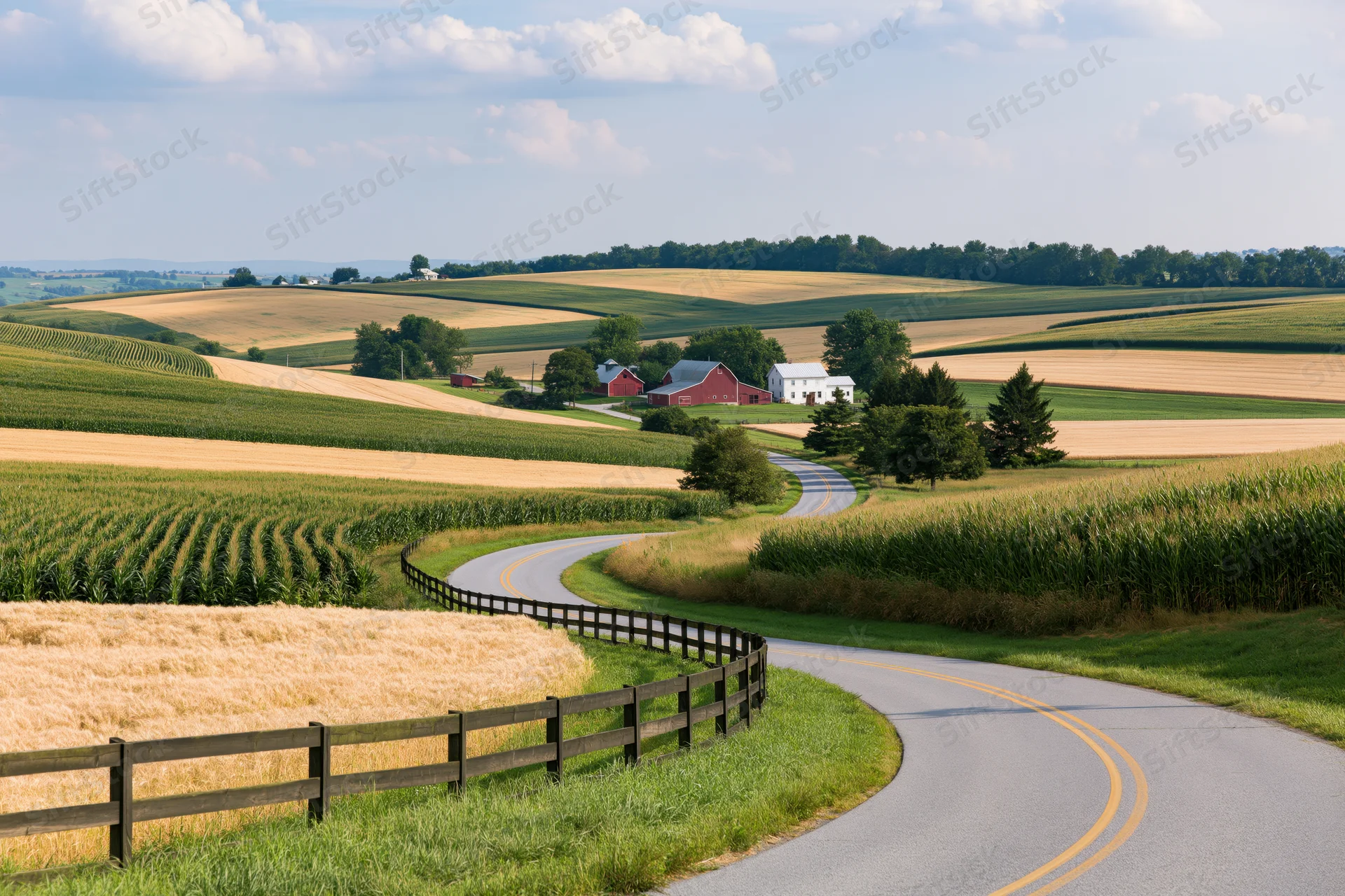 Winding asphalt road curves through rolling cornfields and golden wheat near a red barn farmstead in the American Midwest