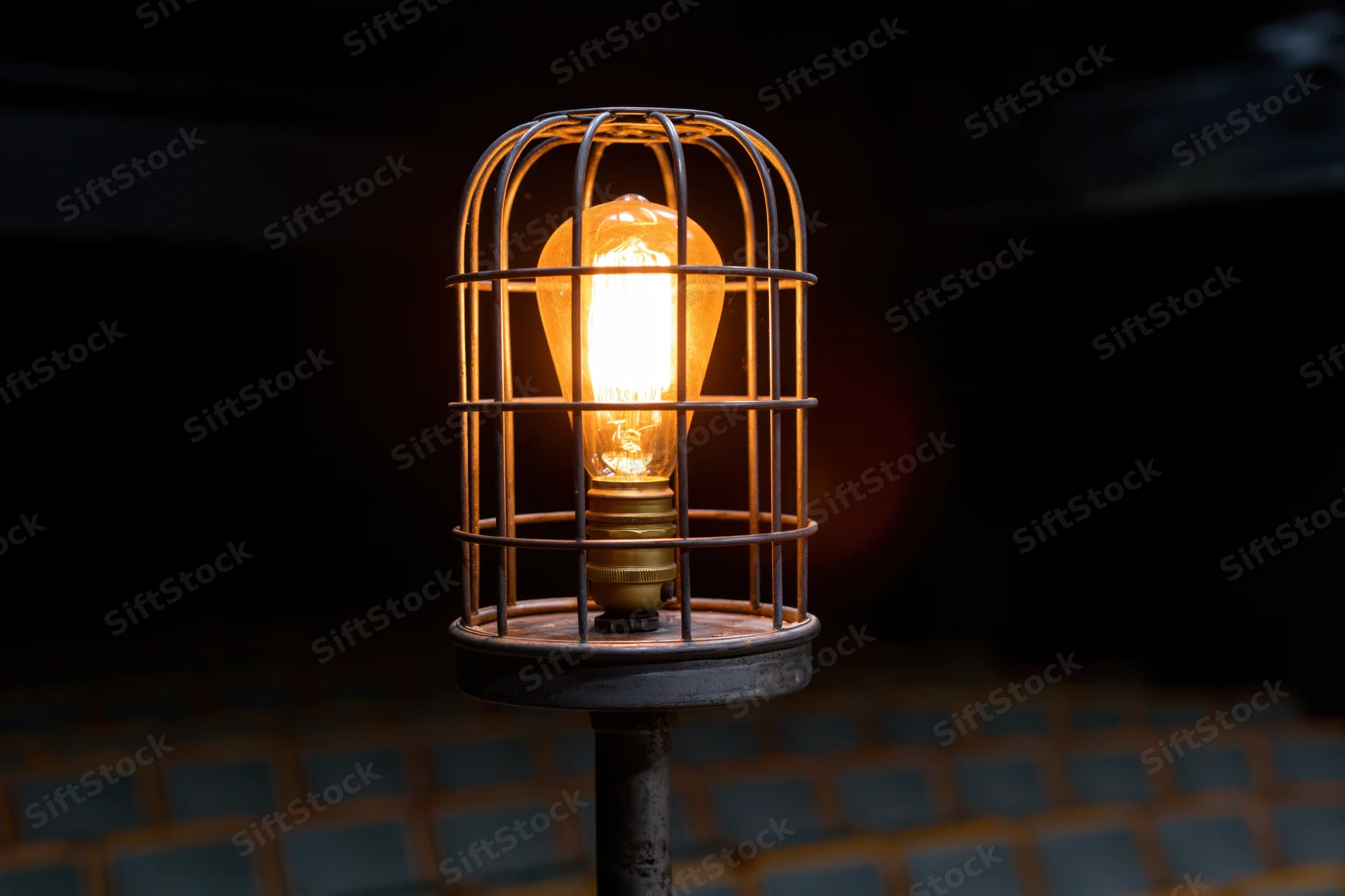 Industrial cage light with glowing Edison bulb on metal stand