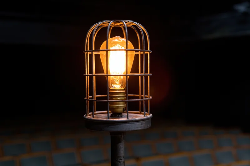 Industrial cage light with glowing Edison bulb on metal stand