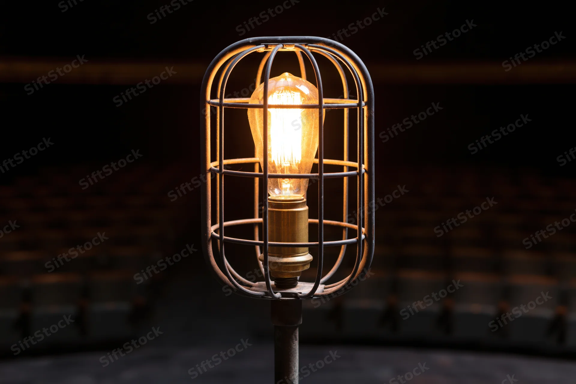 Industrial cage work light glowing warmly on metal stand in dim interior