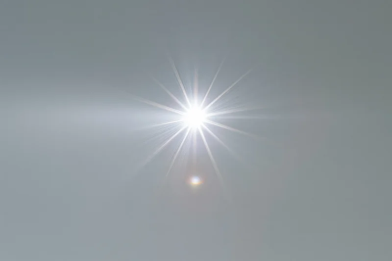 Bright lens flare burst centered on a plain light gray background