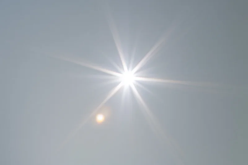 Bright lens flare burst centered on a plain light gray background