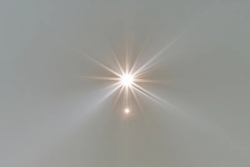 Bright lens flare burst centered on a plain light gray background