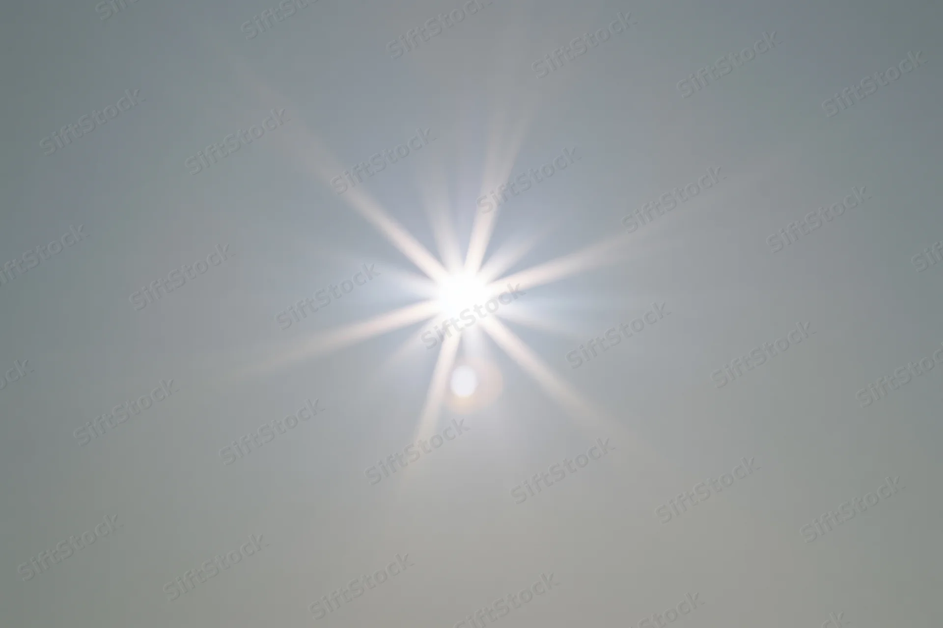 Bright lens flare burst centered on a plain light grey background