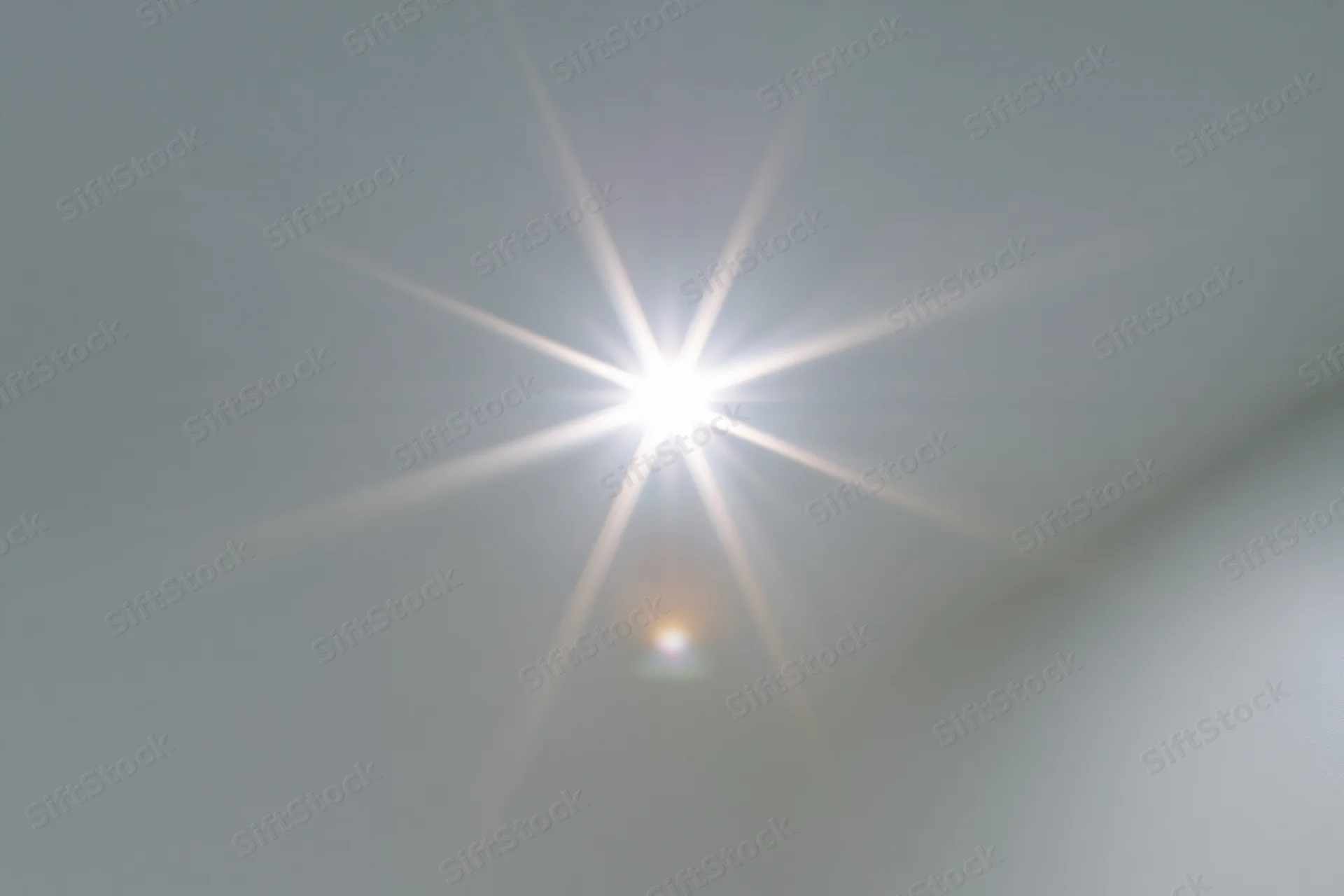 Bright lens flare burst centered on a plain light gray background