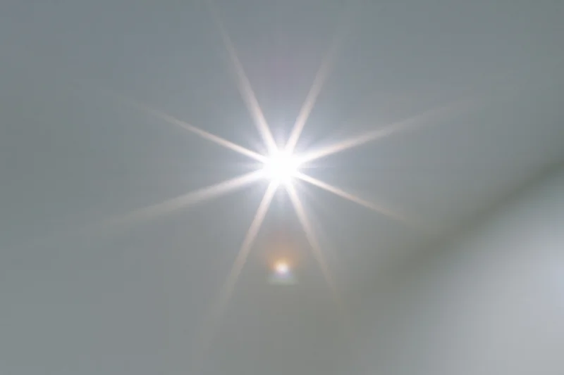 Bright lens flare burst centered on a plain light gray background