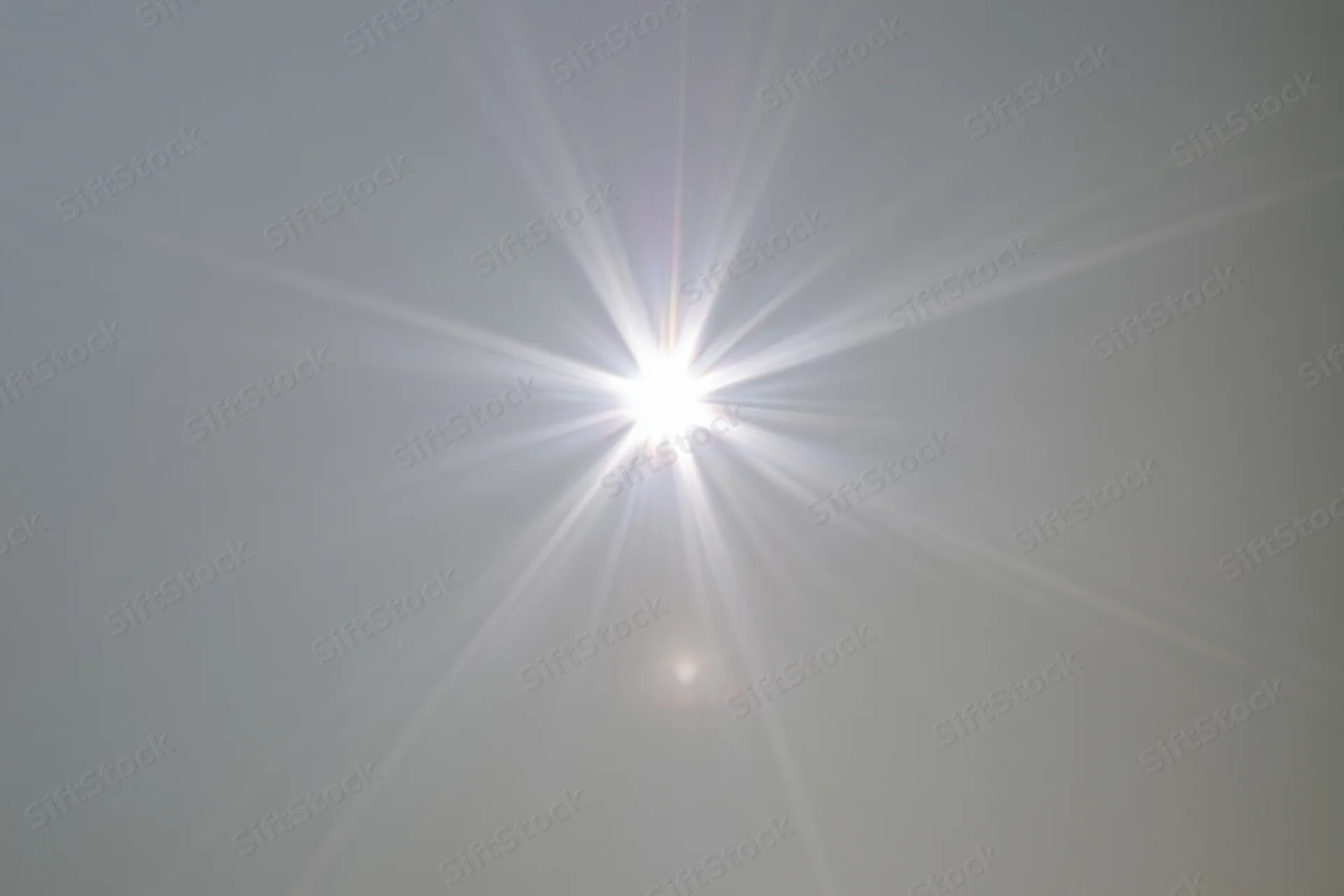 Bright lens flare burst centered on a plain light grey background