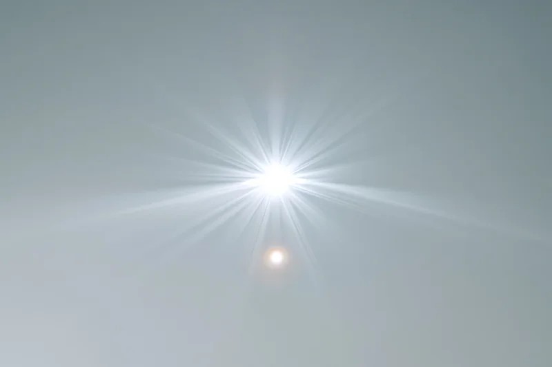 Bright lens flare burst centered on a plain light grey background