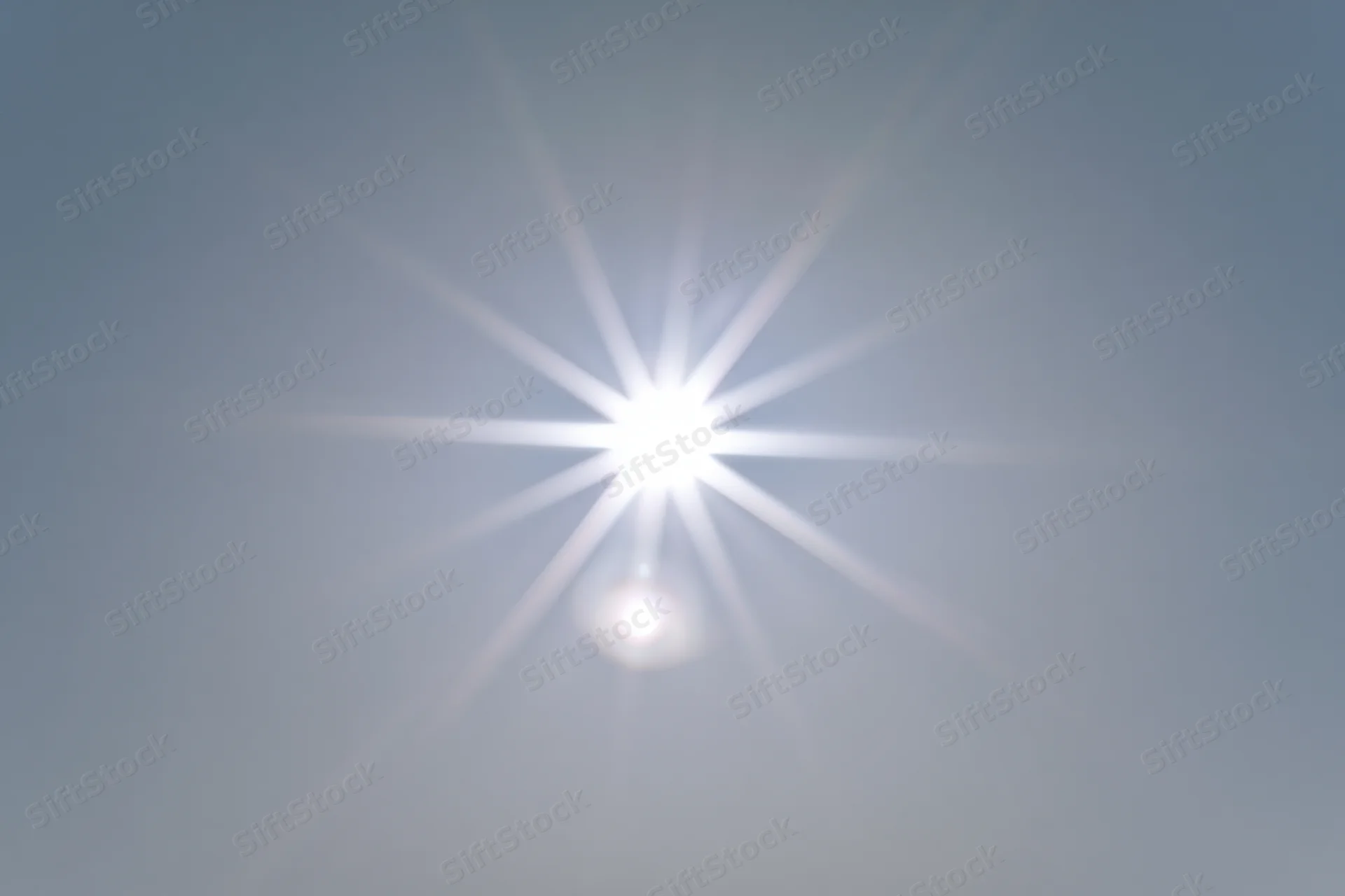 Bright lens flare burst centered on a plain light grey background with copyspace