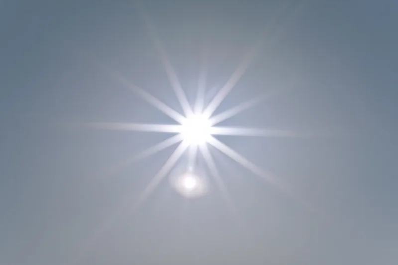 Bright lens flare burst centered on a plain light grey background with copyspace