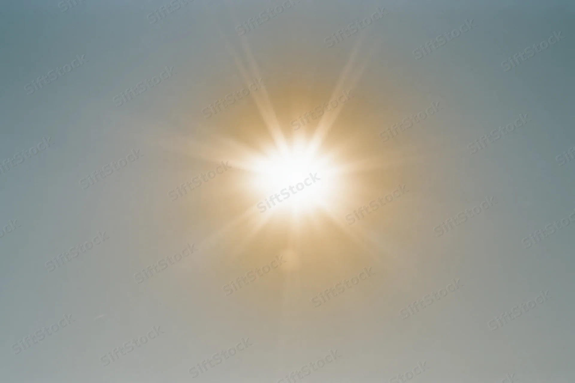 Bright midday sun shining in a pale white sky