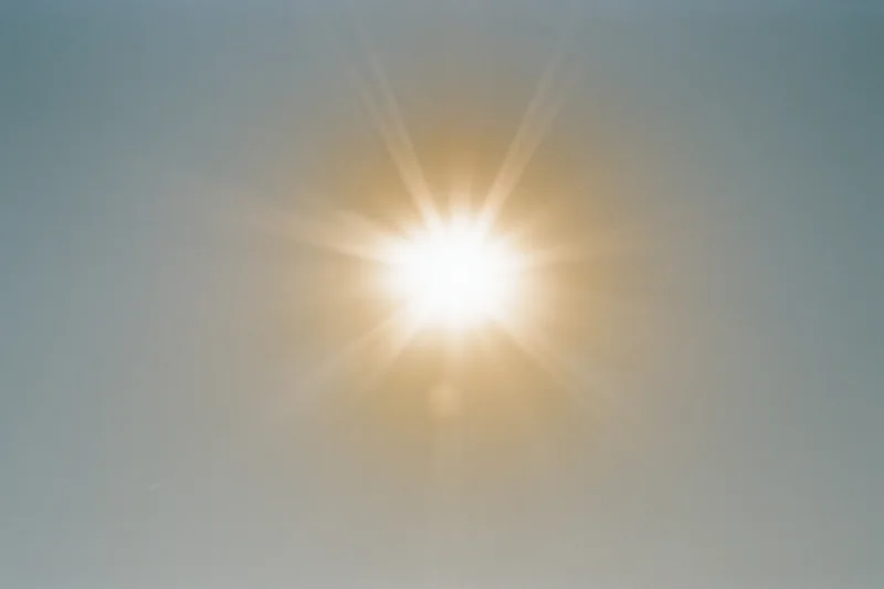 Bright midday sun shining in a pale white sky