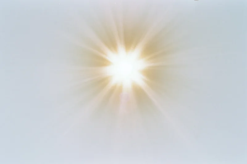 Bright midday sun radiating light against a pale white sky