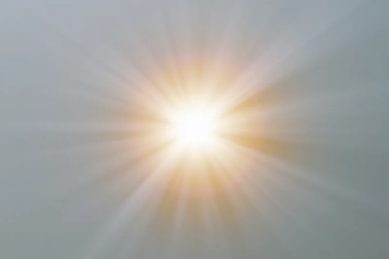 Bright sunburst lens flare radiating light rays from center frame