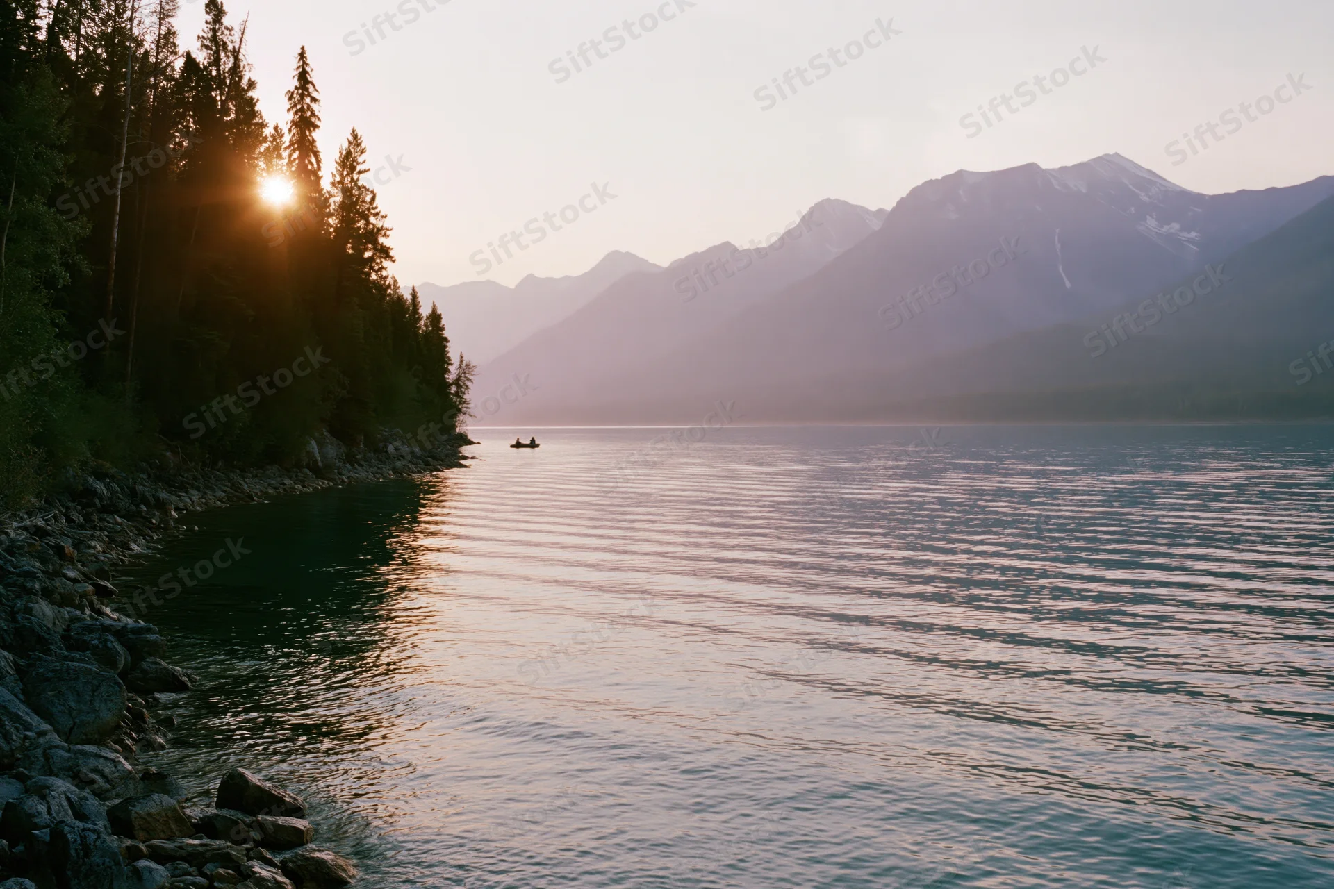 Calm alpine lake reflecting sunset light with rocky shore and evergreen forest, distant mountains in background, small kayak on water
