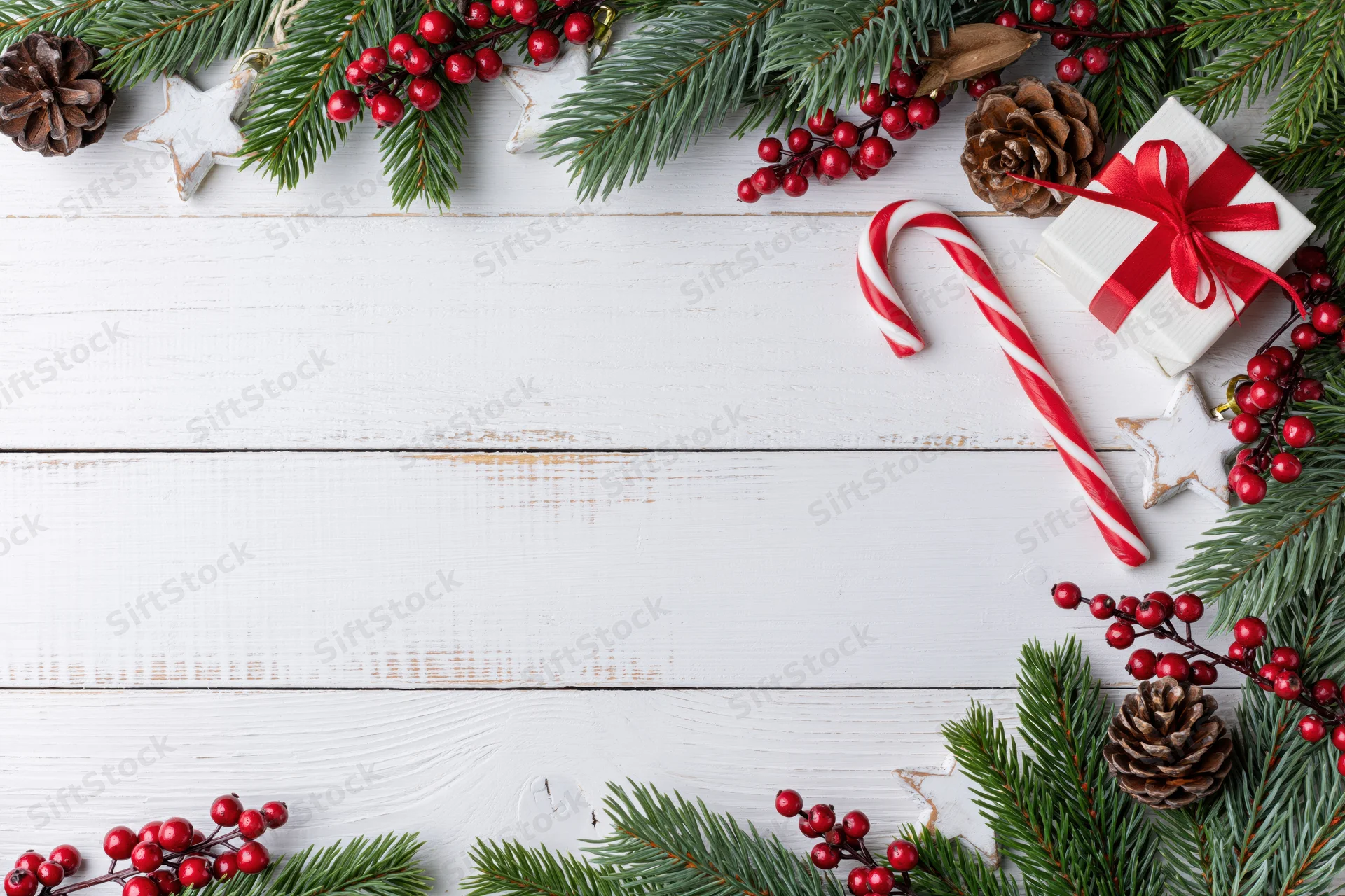 Christmas holiday flat lay with pine branches and red berries arranged on white wooden surface