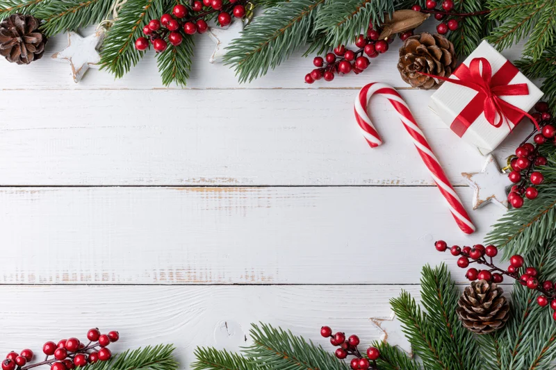 Christmas holiday flat lay with pine branches and red berries arranged on white wooden surface