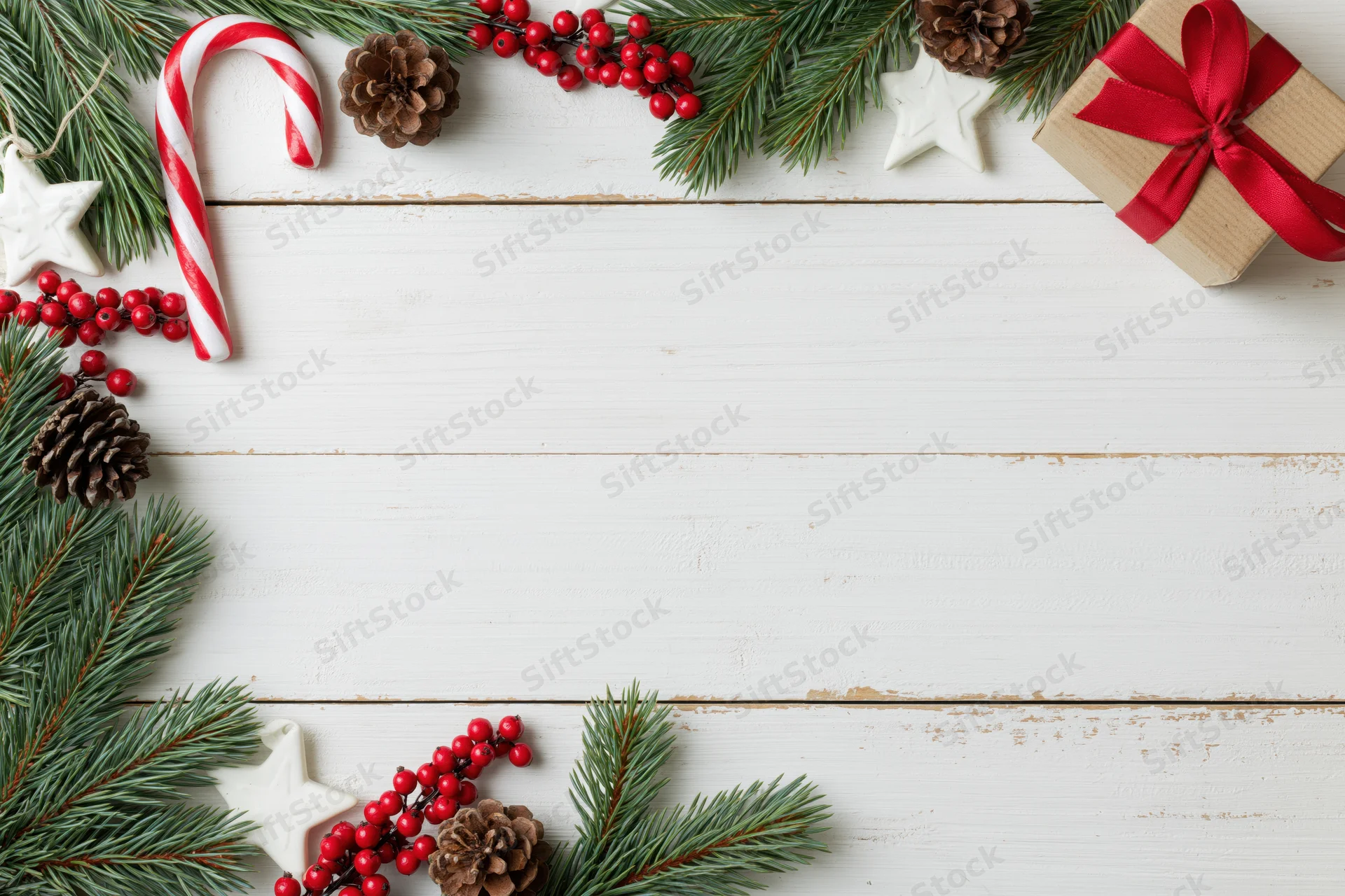 Christmas holiday flat lay with pine branches and red berries arranged on white wooden surface
