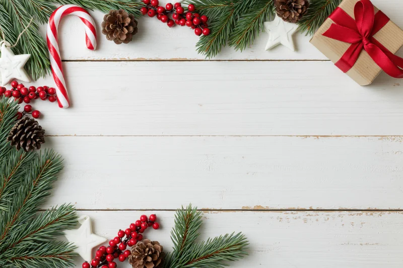 Christmas holiday flat lay with pine branches and red berries arranged on white wooden surface