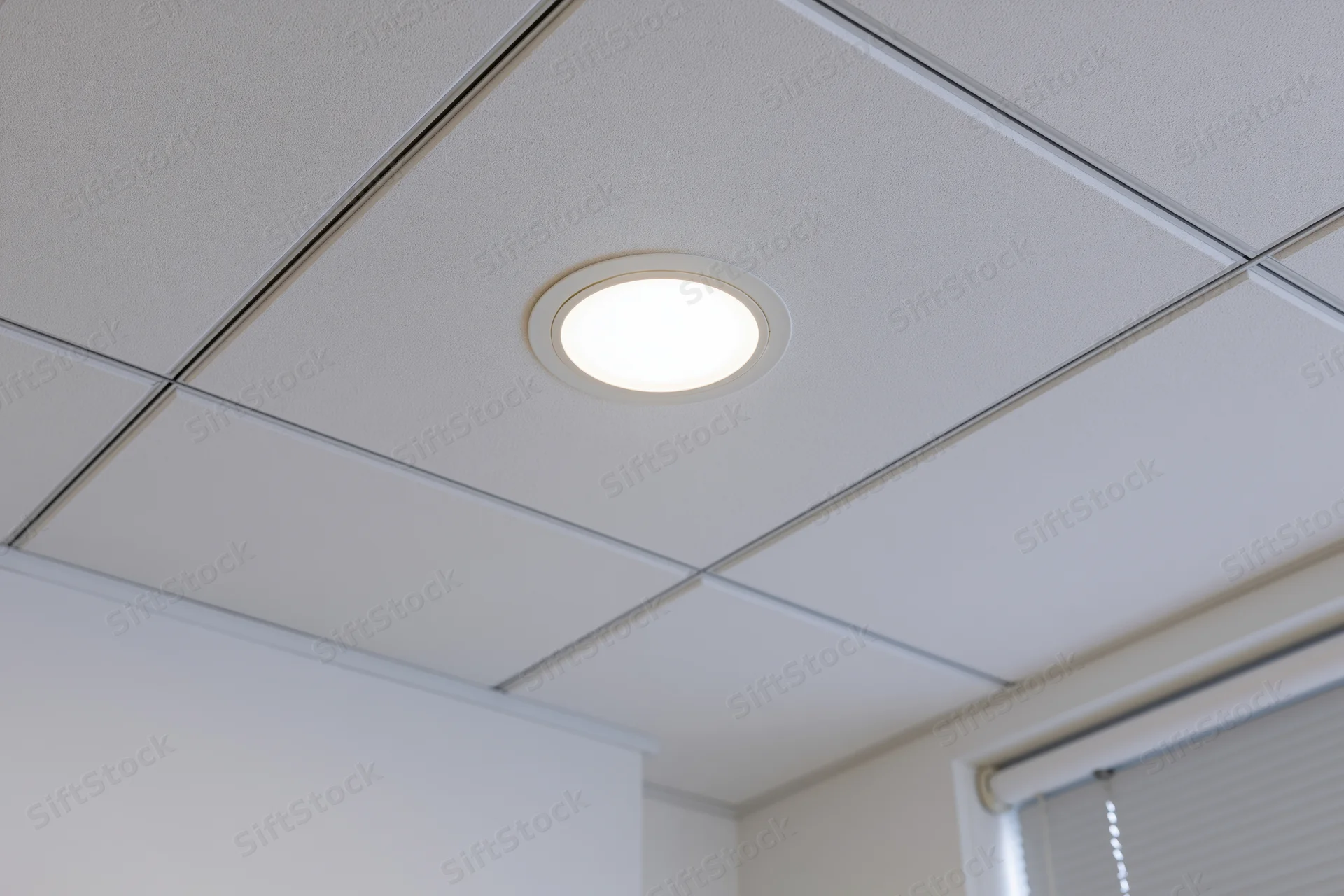 White drop ceiling with recessed circular light in office interior