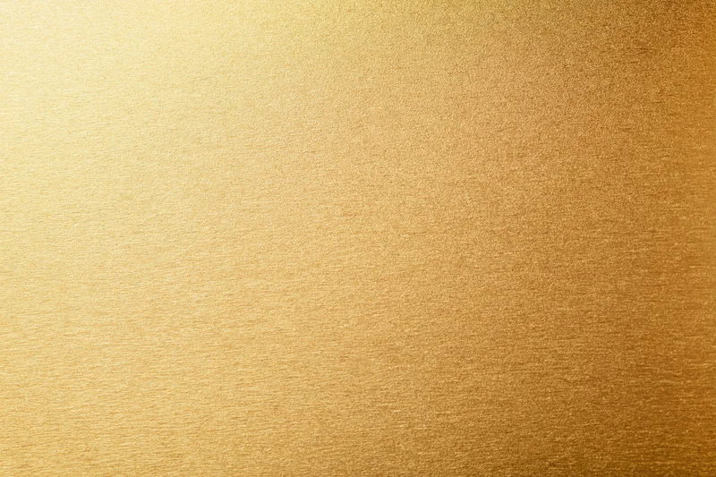 Close-up flat lay of a brushed gold metallic surface filling the frame