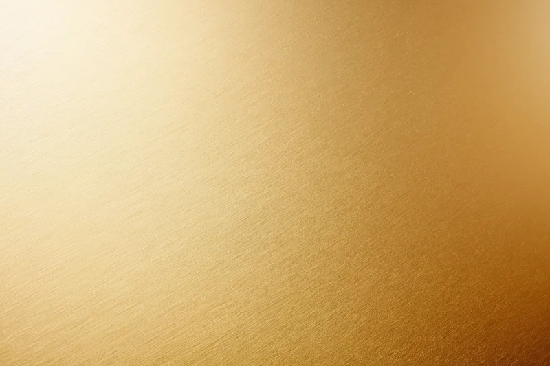 Close-up flat lay of a brushed gold metallic surface filling the frame