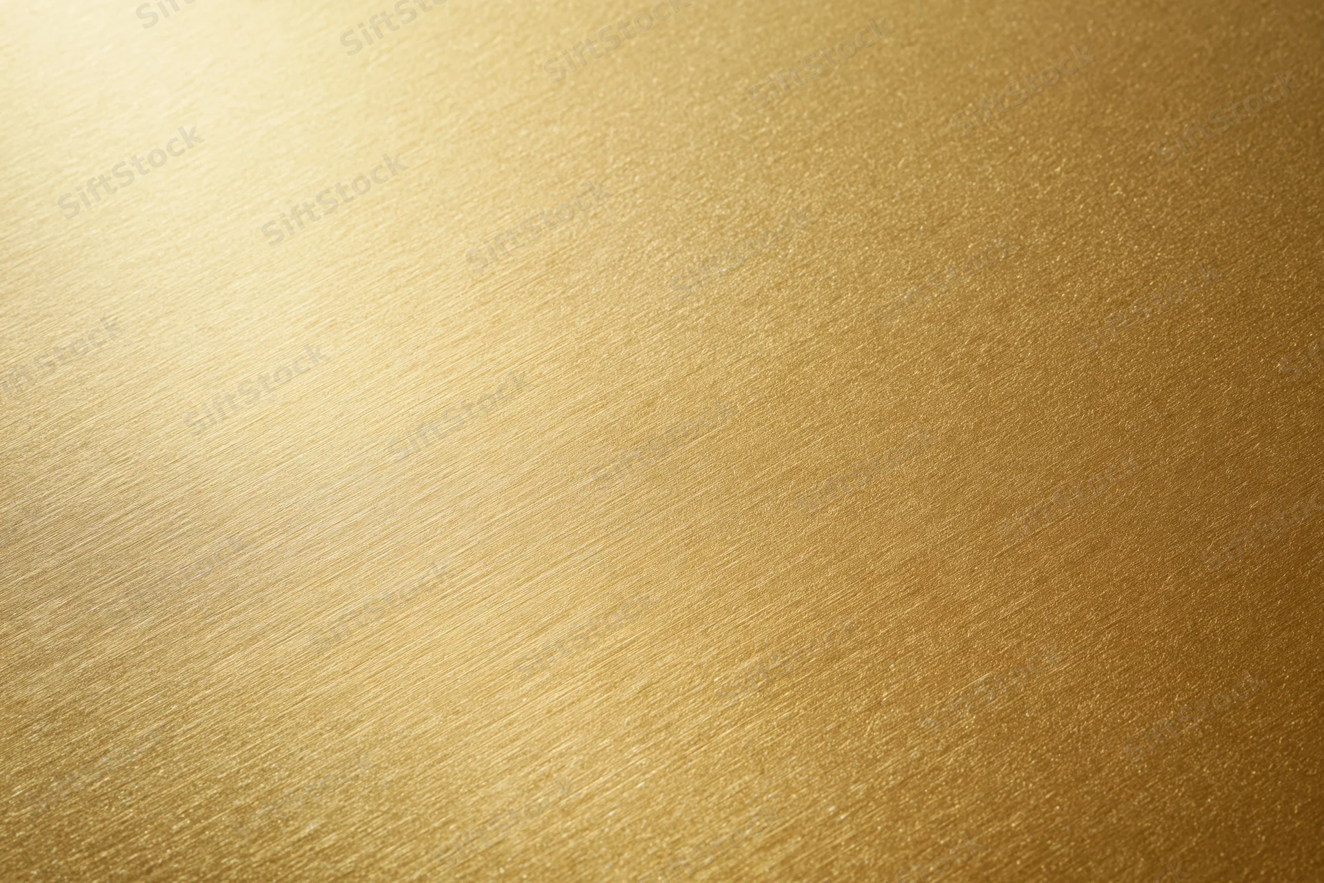 Close-up flat lay of a brushed gold metallic surface filling the frame