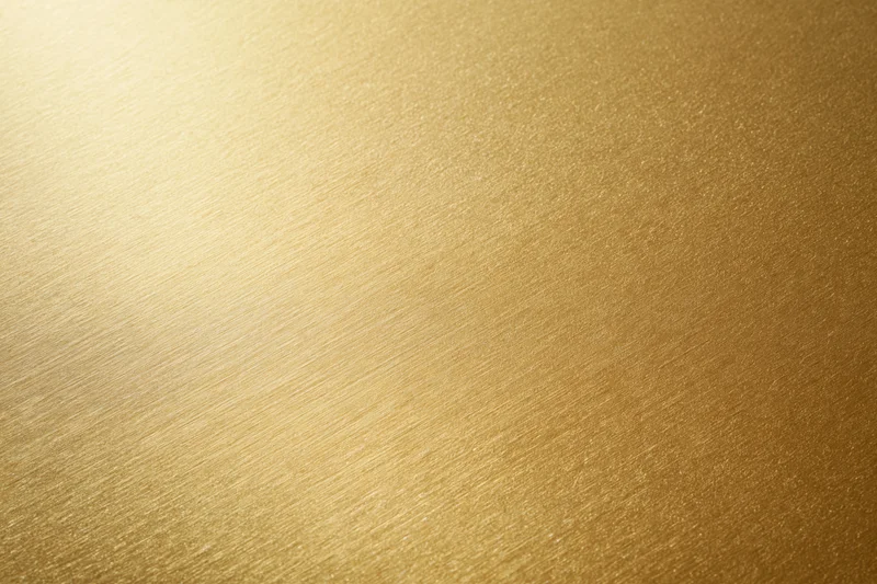 Close-up flat lay of a brushed gold metallic surface filling the frame