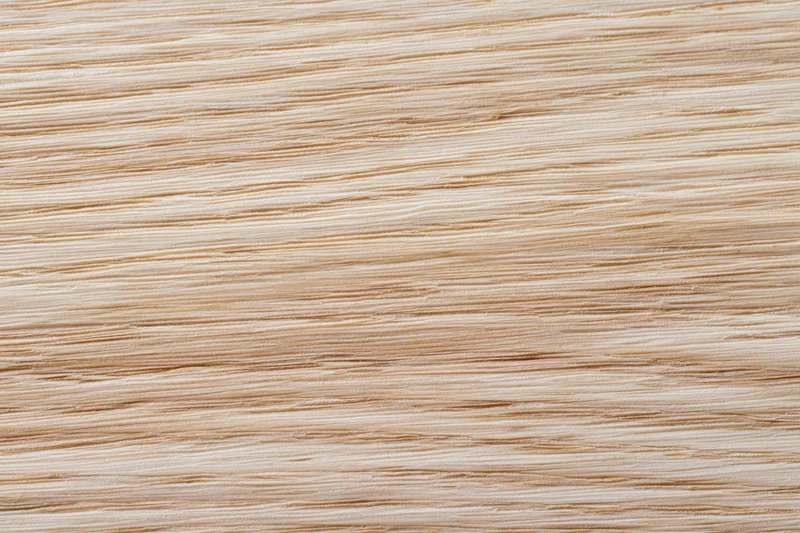 Close-up flat lay of light blonde wood veneer surface showing fine horizontal grain pattern