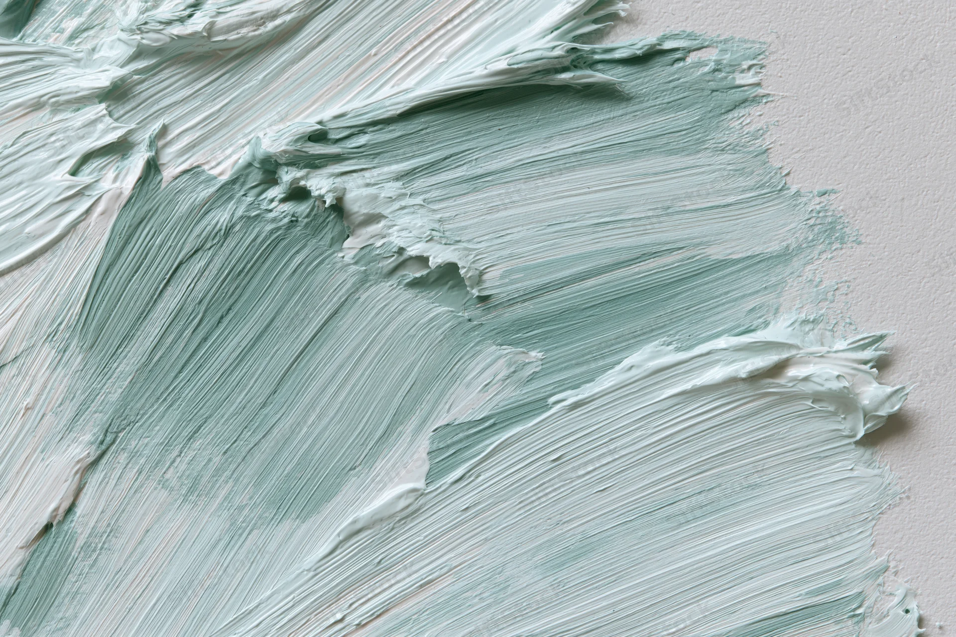 Close-up of gestural paint strokes on white canvas showing textured layers of mint green and white acrylic paint
