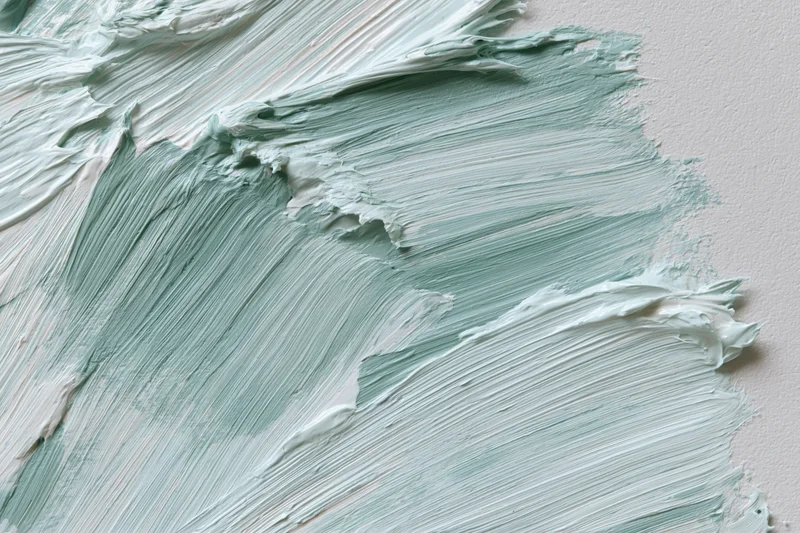Close-up of gestural paint strokes on white canvas showing textured layers of mint green and white acrylic paint
