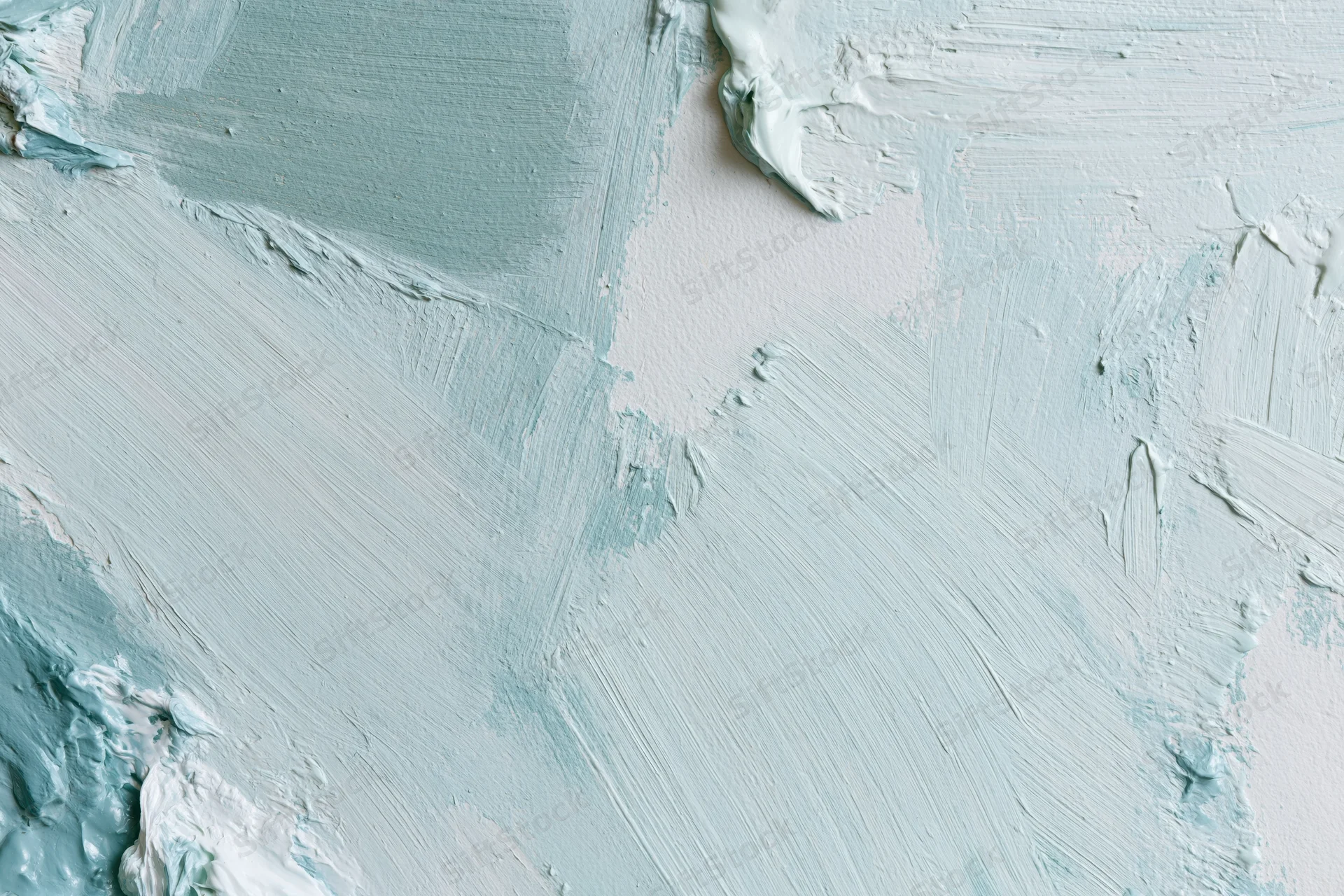 Close-up of a white canvas with loose gestural brushstrokes of blue and white paint in a flat lay arrangement
