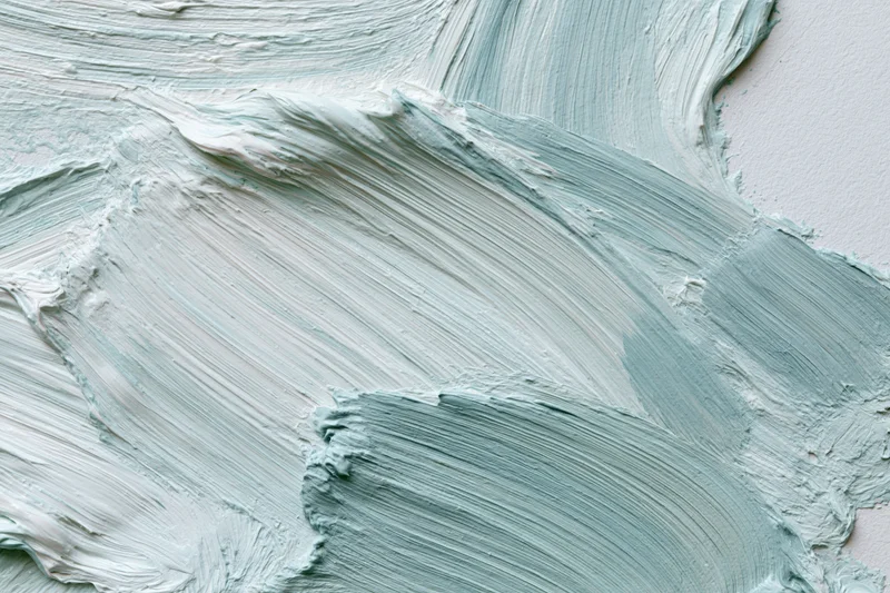 Close-up of thick gestural paint strokes on a white canvas surface