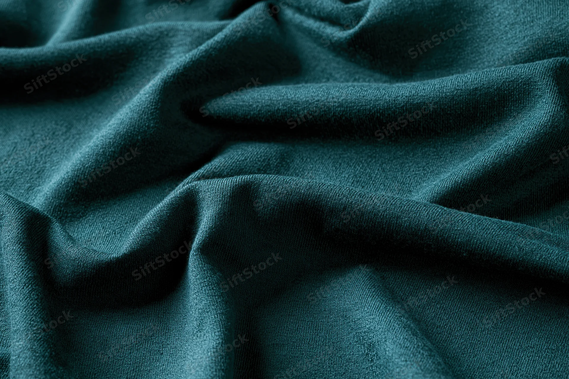 Close-up of deep teal-green fabric with natural wrinkles filling the frame