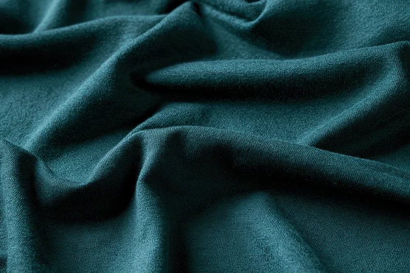 Close-up of deep teal-green fabric with natural wrinkles filling the frame