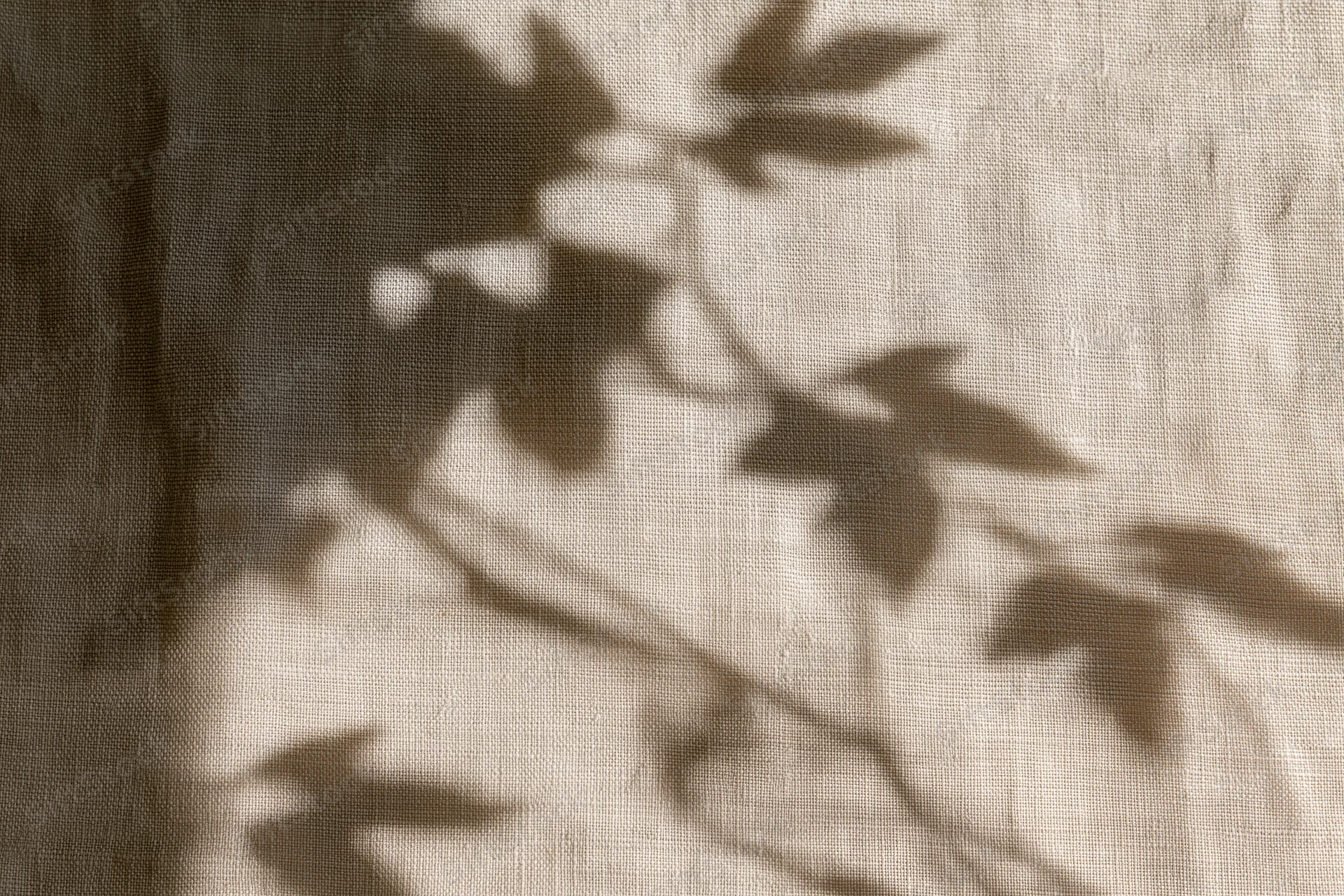 Natural linen fabric with leaf shadows cast across its surface