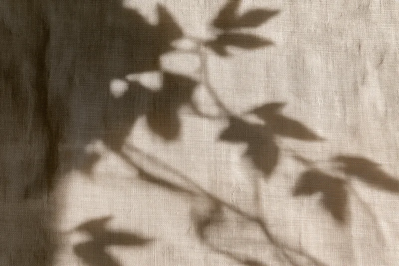 Natural linen fabric with leaf shadows cast across its surface
