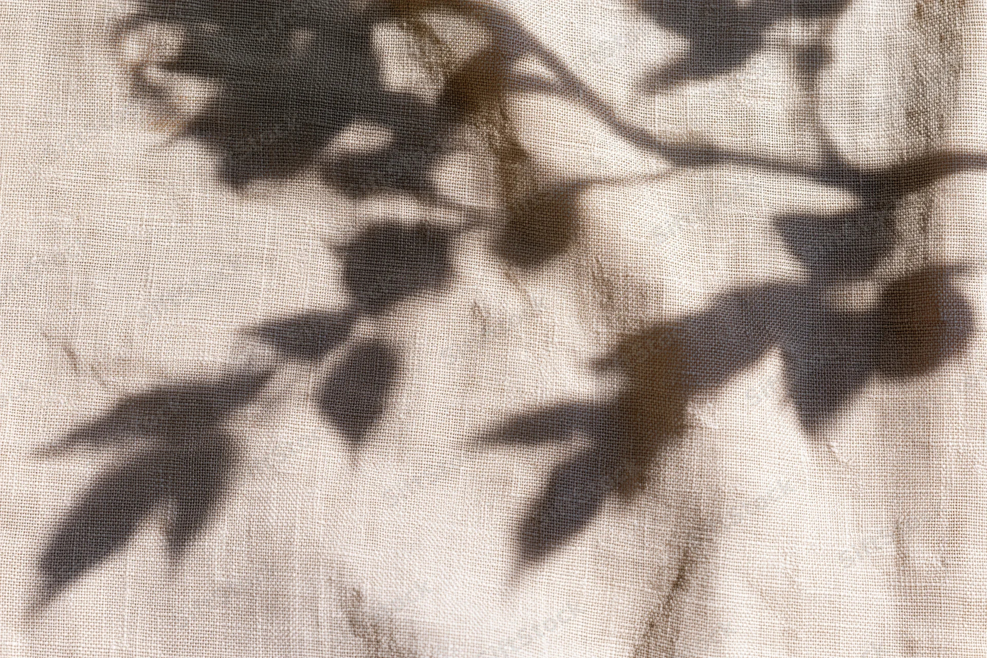 Shadow of leaves on natural linen fabric in flat lay arrangement
