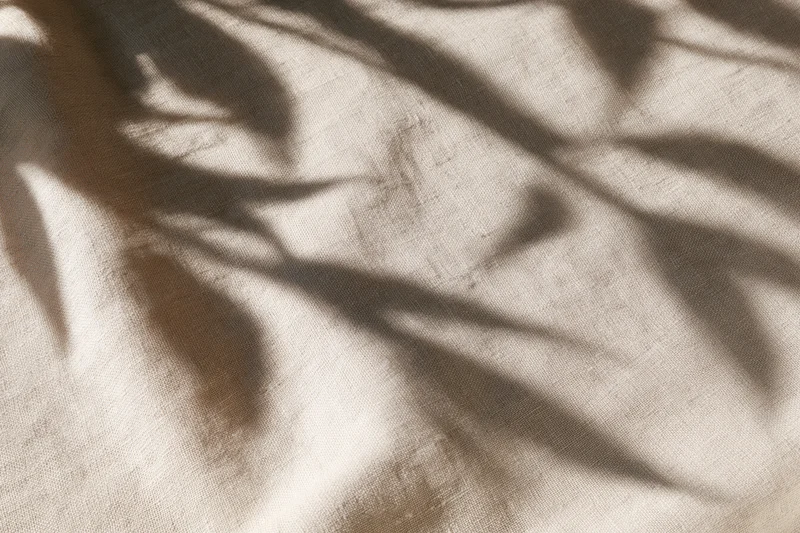 Natural linen fabric with leaf shadows in flat lay arrangement