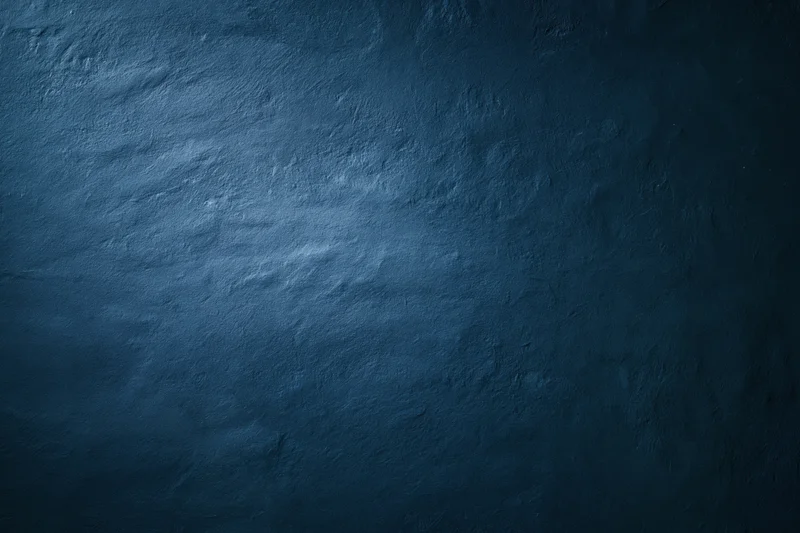 Close-up of a plain painted concrete wall with matte blue finish and textured surface
