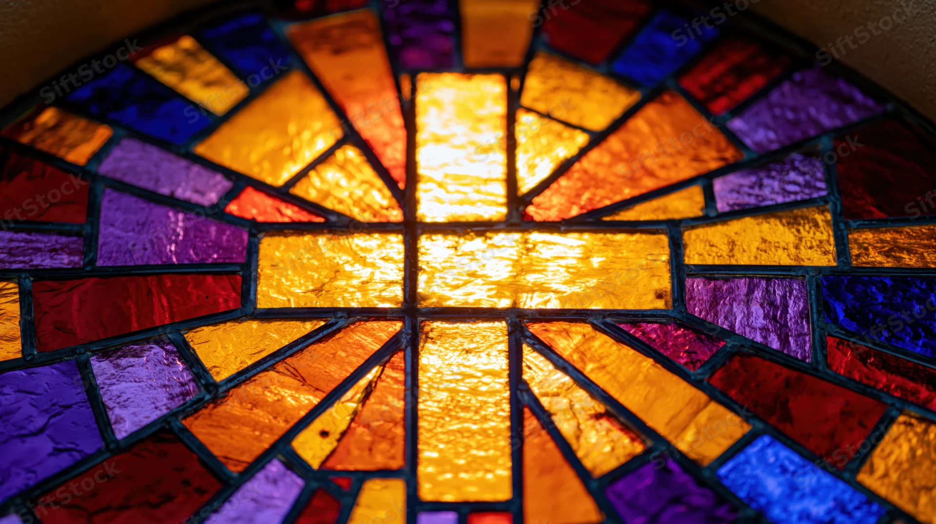Stained glass church window with a central cross radiating colorful light