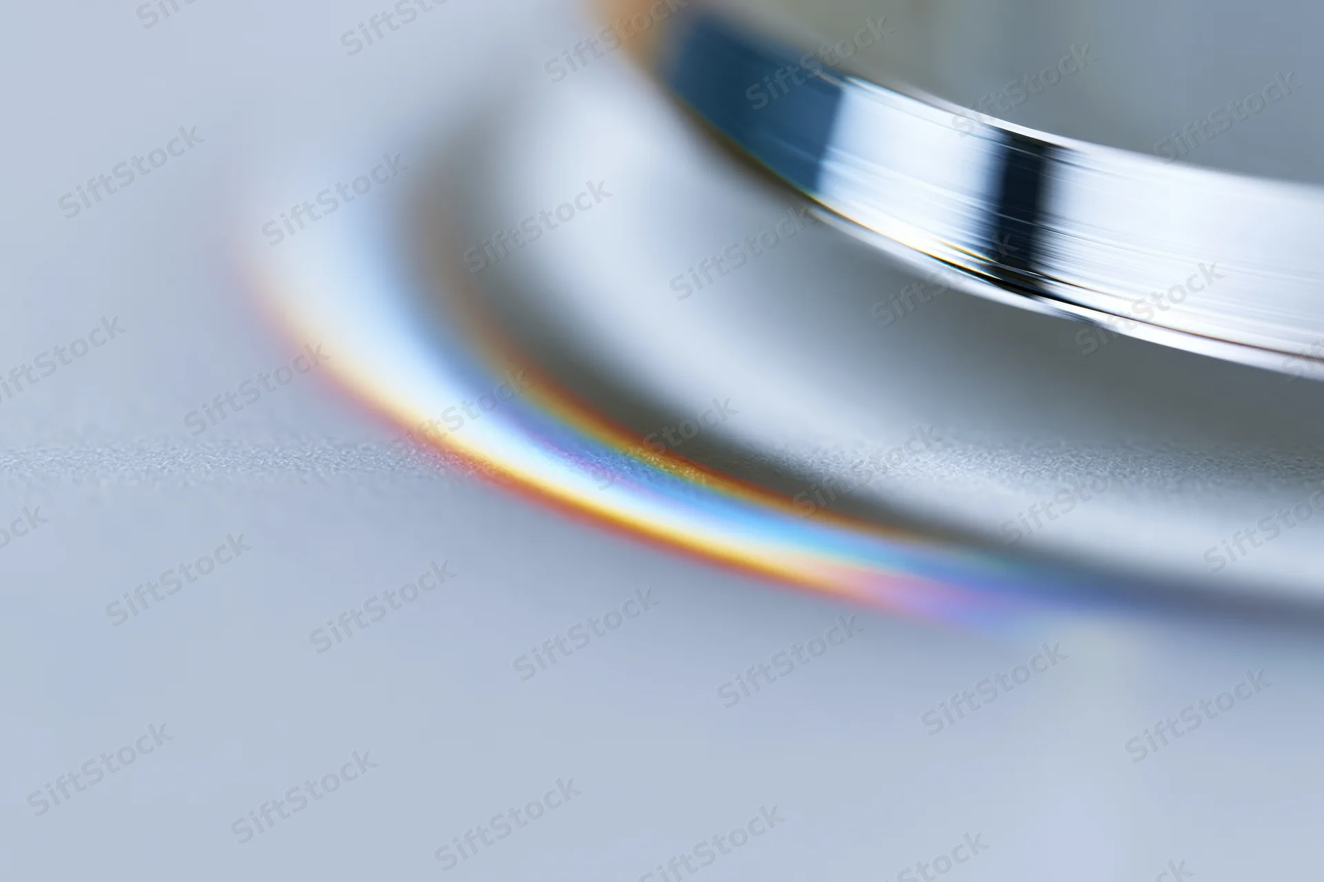 Close-up of a glass prism edge casting a rainbow spectrum on a smooth surface