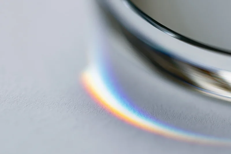 Close-up of a glass prism edge casting a rainbow spectrum on a white surface