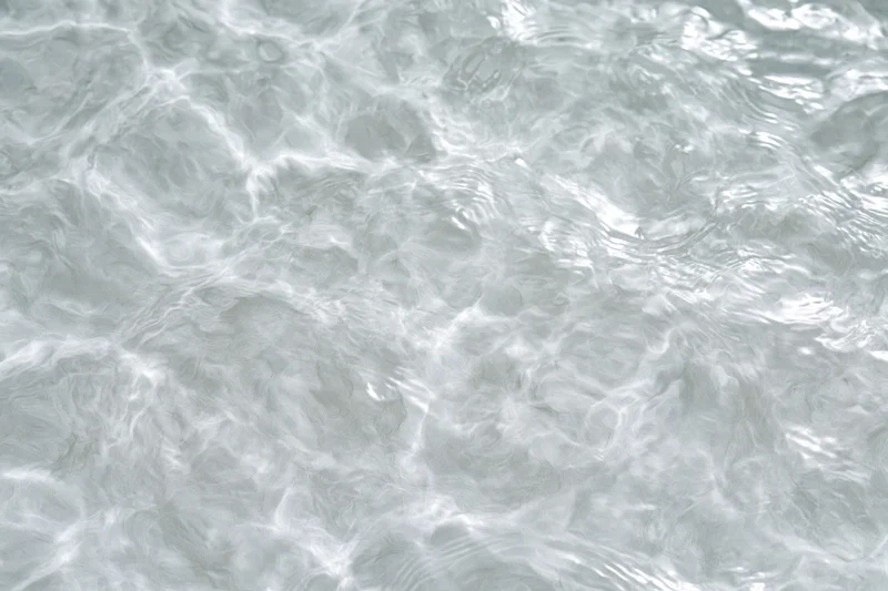 Calm clear water surface with gentle ripples and light reflections
