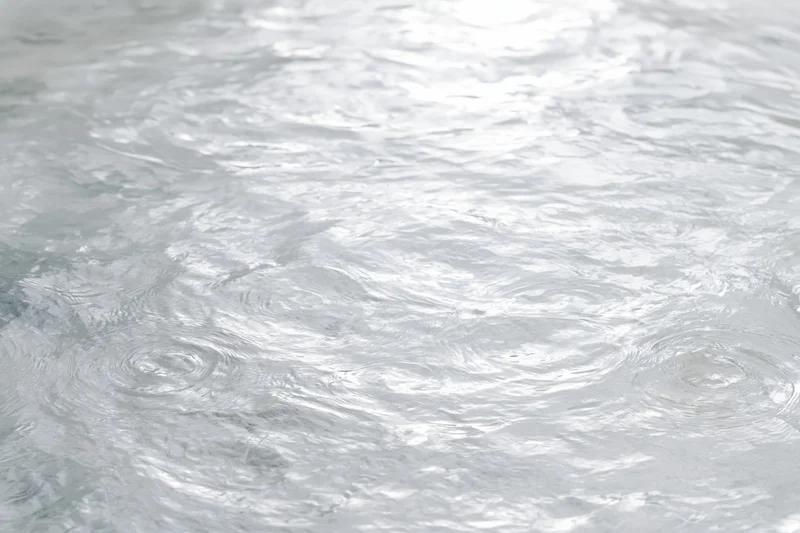 Calm clear water surface with gentle ripples and circular disturbances