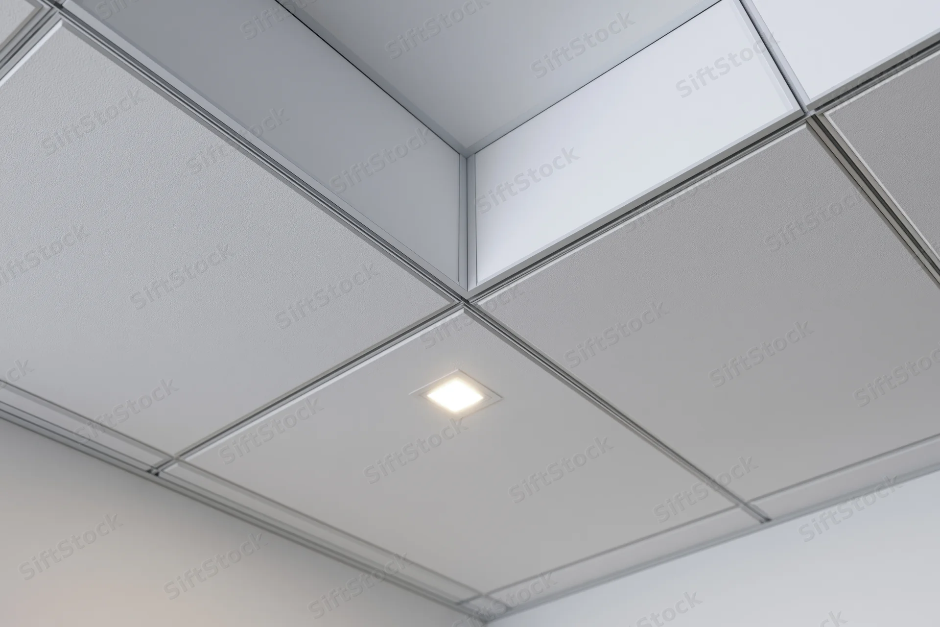 Corner junction of a modern office drop ceiling with recessed light and grid structure